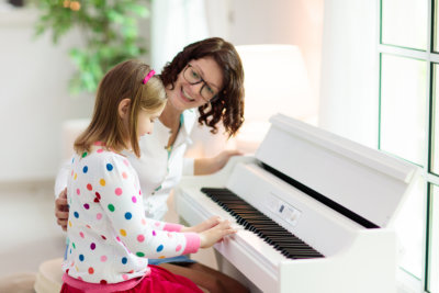 Child playing piano. Kids play music. Classical education for children. Art lesson. Little girl at white digital keyboard. Instrument for young student. Music class in school or at home