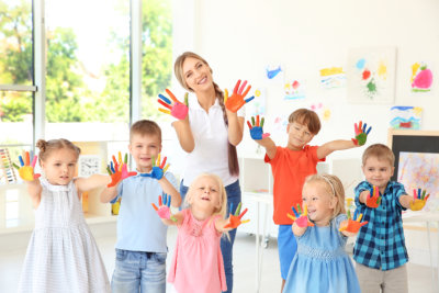 Children and teacher with hands in paint at art lesson